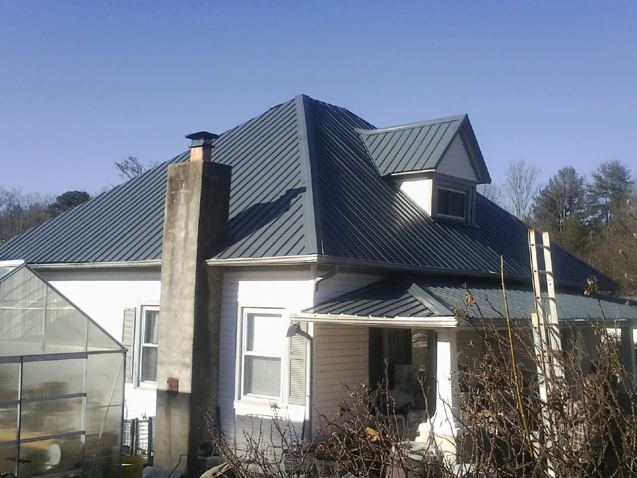 Dark blue standing seam metal roof on a white farmhouse with dormer — Slate & Tile Roof Repair by Roofing Brothers in Guysville