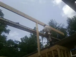 Carpenter setting a ridge beam over a new addition frame — Ice Dam Removal by Roofing Brothers in Guysville