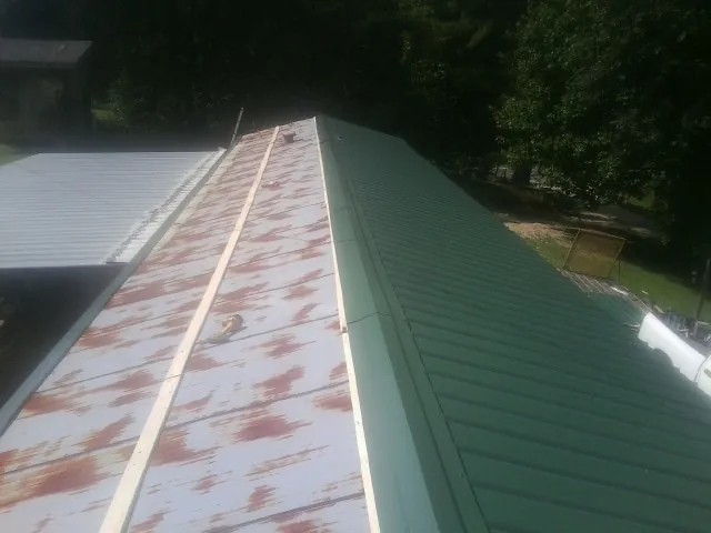 Old rusted panels beside newly installed green metal roofing — Wind Damage Roof Repair by Roofing Brothers in Guysville