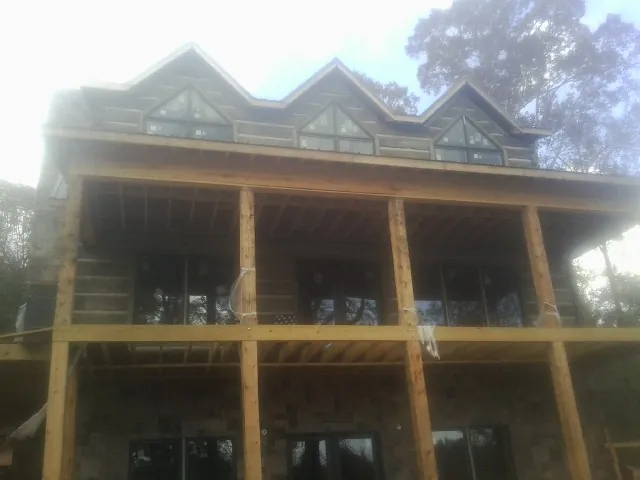 Dormers and porch framing on a large log home under construction — Roof Coating work by our crew in Guysville