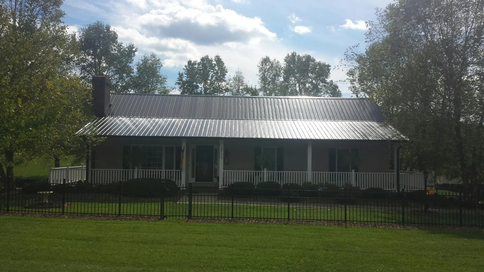 Gray metal roof on a brick ranch with a full width front porch — Gutter Guard Installation work by our crew in Guysville