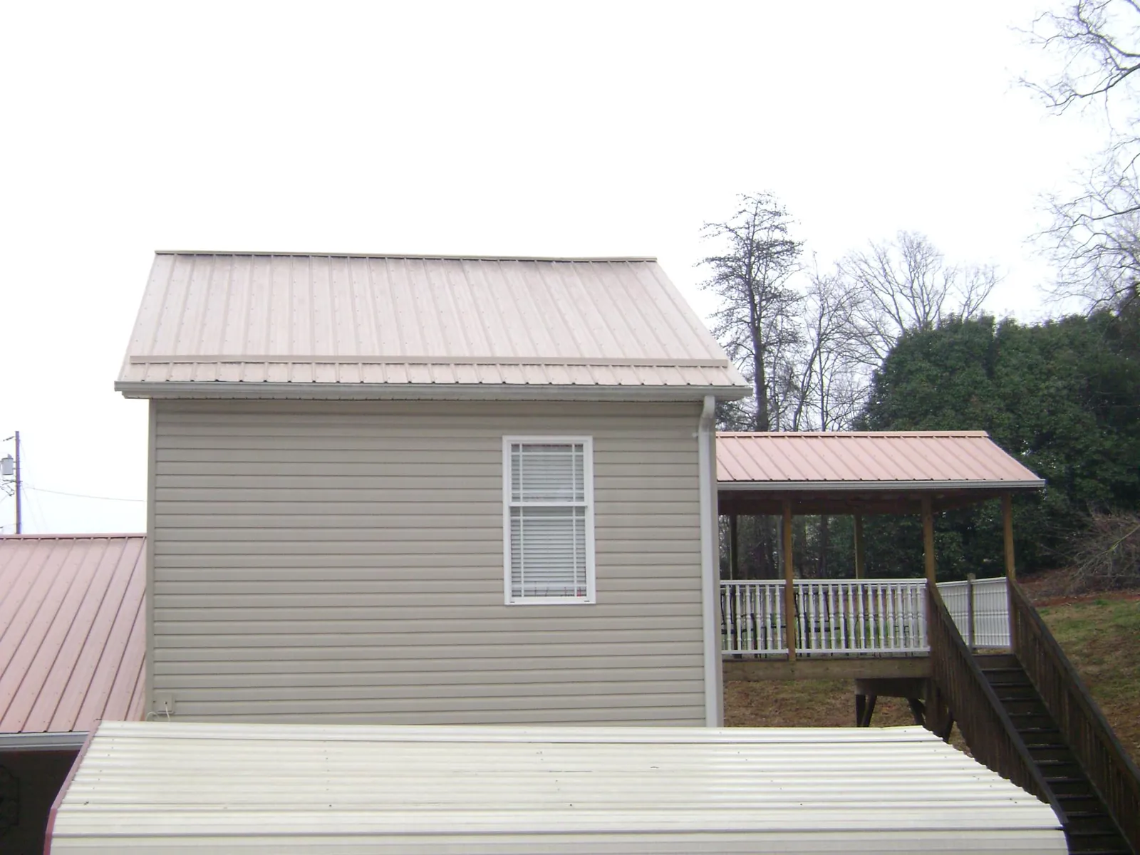Tan metal roofs on a two story addition and attached porch, from a Roof Replacement job in Guysville