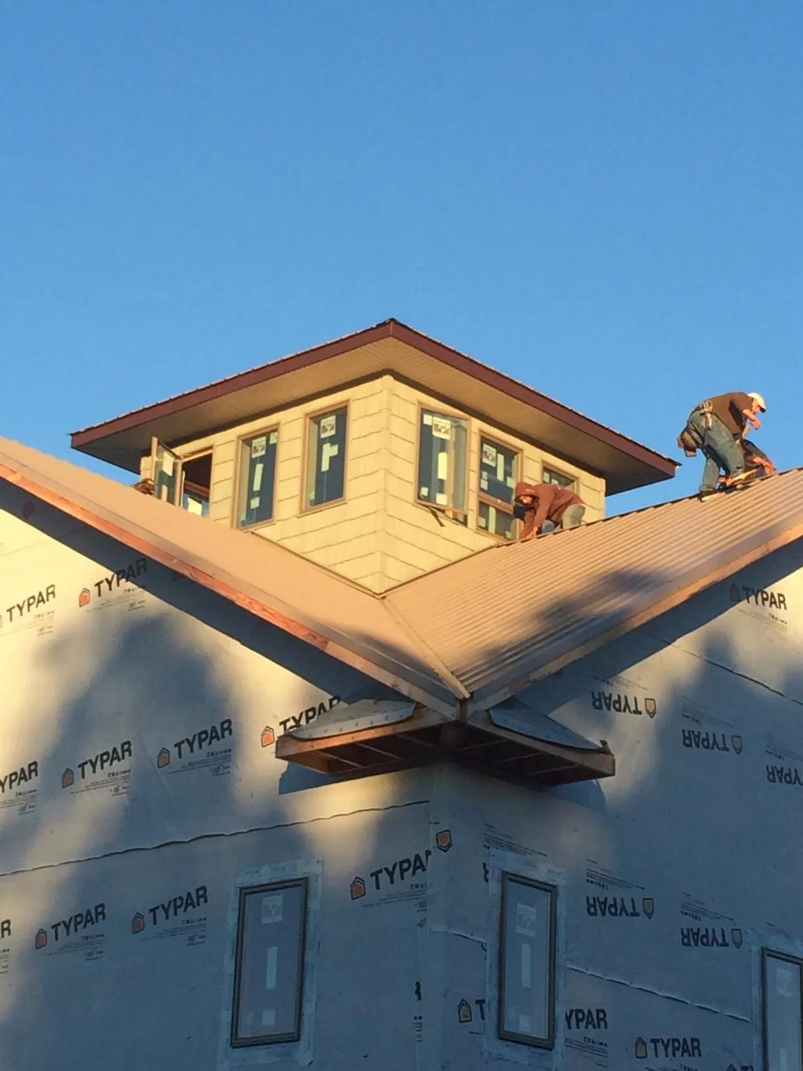 Roofers working around a rooftop cupola on a new metal roof at sunset — Roof Waterproofing in Guysville by Roofing Brothers